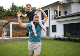 Obraz premium Father with daughters playing outdoors in the backyard, running.