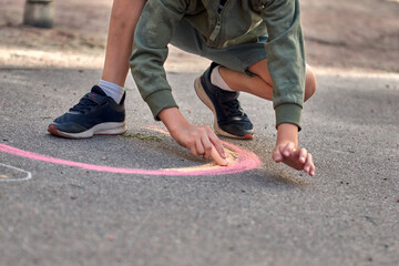 Kids paint outdoors. Boy drawing a rainbow colored chalk on the asphalt the playground