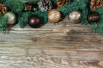 Coniferous tree branches along with cones and toys for the Christmas tree lie on an old wooden table. Below is a place for text. Holiday card concept