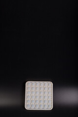 White silicone antistress toy. Pop bubble on black with copy space. Pop it on black background.