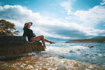 Amazing view of a brunette sitting on a rock near the sea. Amazing summer weather in Croatia , vis...