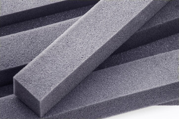 square piece of dark sponge foam. black foam block material on a white background