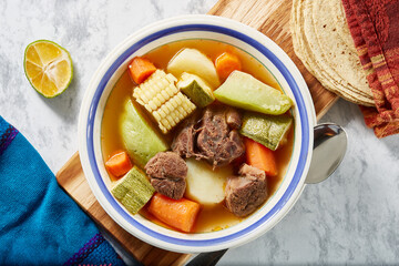 Mole de olla, red beef broth with meat, carrot, corn, pumpkin, potato, traditional Mexican dish