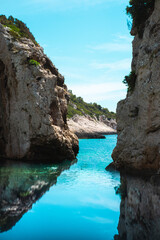 Two iconic rocks of the Stiniva bay in Croatia. Beautiful blue summer day, reflection of the rocks on the crystal clear blue sea