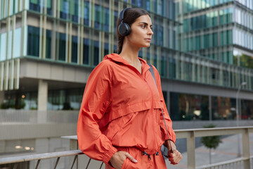 Motivated sportswoman looks with determined expression enjoys workout outdoors has morning exercising routine dressed in activewear listens music poses in downtown. Active lifestyle concept. © WHstudio Leushin N