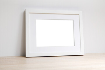 Pusta biała rama na zdjęcia na komodzie oparta o ścianę