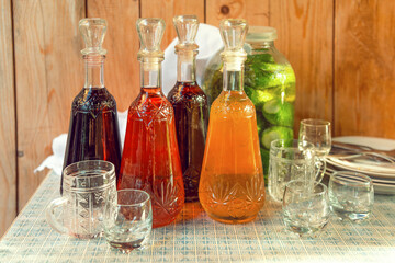 Various wines in decanters, a jar of cucumbers and glass mugs on the table.