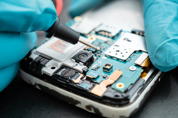 Technician repairing inside of mobile phone by soldering iron. Integrated Circuit. the concept of...