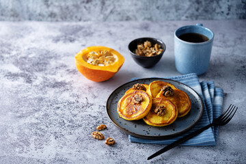 Pumpkin pancakes with walnuts and caramel sauce in a plate