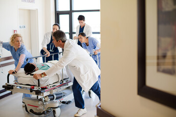 Obraz premium Doctors rushing patient on gurney in hospital corridor