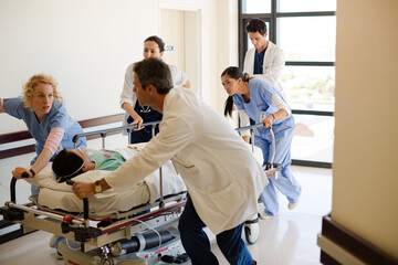 Doctors rushing patient on gurney in hospital corridor - obrazy, fototapety, plakaty