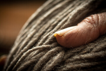 Dedo de anciano sobre hilo de lana natural