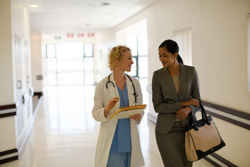 Obraz premium Doctor and businesswoman walking in hospital corridor