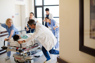 Doctors rushing patient on gurney in hospital corridor