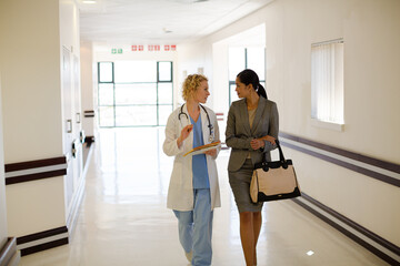 Fototapeta premium Doctor and businesswoman walking in hospital corridor