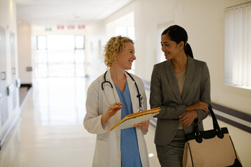 Doctor and businesswoman walking in hospital corridor