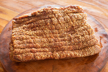 close up appetizing crispy pork belly placed on wooden chopping board