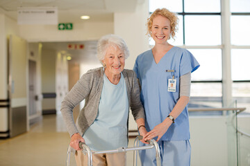 Nurse helping senior patient with walker in hospital corridor