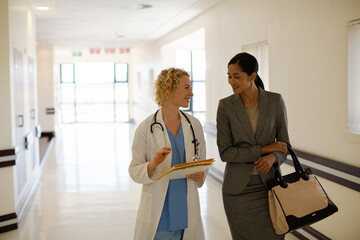 Doctor and businesswoman walking in hospital corridor