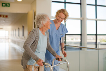 Nurse helping senior patient with walker in hospital corridor