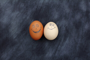 pair of smiling eggs on dark background top view. together when darkness is around