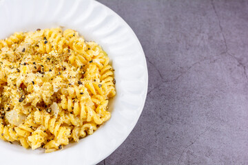 Homemade fusilli white cream sauce in the white dish on dark table. Food concept.