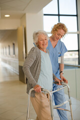 Nurse helping senior patient with walker in hospital corridor