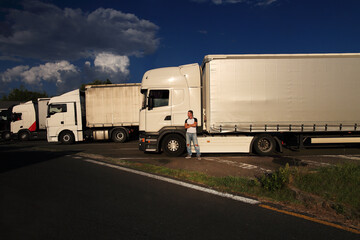 Young truck driver near his truck in the parking lot 