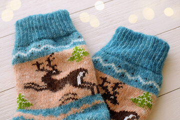 Blue Christmas woolen socks with deers close-up on wooden background and bokeh