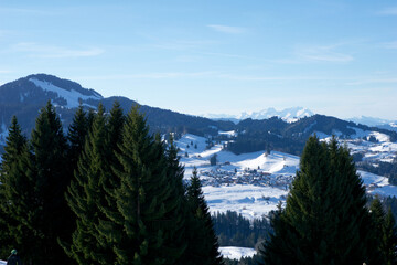 OBERSTAUFEN, GERMANY - 31 DEC, 2017: View of the snowy valley from the Bavarian Alps with conifers in the foreground