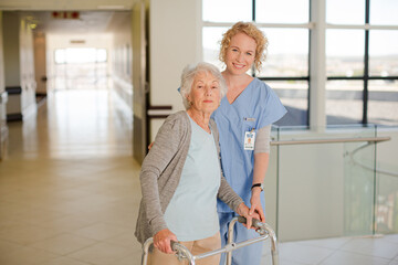 Nurse helping senior patient with walker in hospital corridor