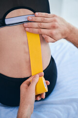 Unrecognized professional osteopath applying kinesio tapes to patients back in his office