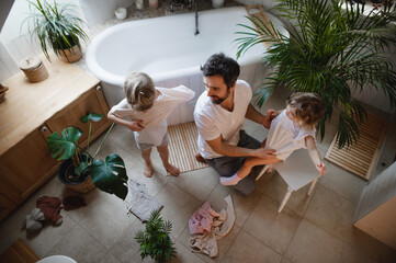 Top view of mature father with two small children indoors at home, getting ready for a bath.