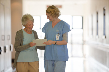Nurse and aging patient reading chart in hospital corridor