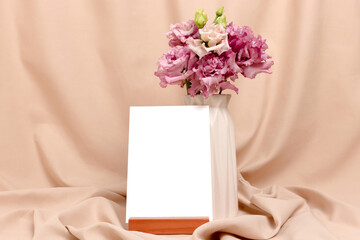 Bouquet of eustoma flowers and blank paper card mockup with copyspace. Greeting card concept for springtime holidays.