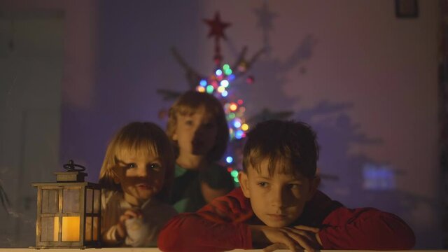 Portrait of one one waiting and two brother joining, thee children looking for Santa, Christmas tree