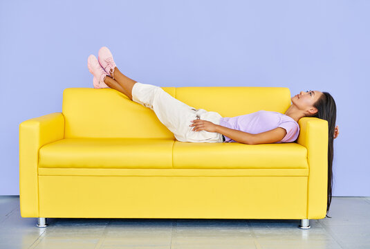 Pretty Asian Woman Relax After Lying On Yellow Sofa