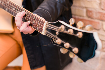 Street musician playing guitar. Selective focus on left hand. Guitar neck close up.