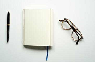 notebook with space for text, office, blue bookmark, brown glasses, pen, on a white background, top photo