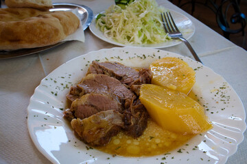 Traditional Balkan dinner - meat stewed in a special pot, sac, served with kajmak cheese and stewed vegetables, fresh baked bread and coleslaw salad