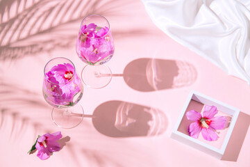 Creative composition made of two glasses with hibiscus flower water on pastel pink background with palm tree leaves shadows. Summer and refreshment concept © Androlia