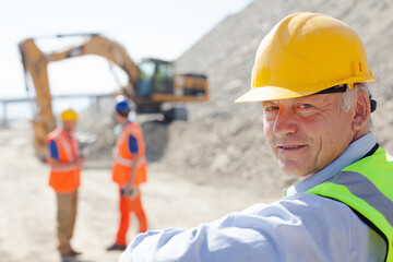 Businessman in hard hat smiling in quarry