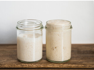 Two glass jars with wheat sourdough starters in different hydration levels. Starter 100 percent hydration (right) and starter with higher hydration (left). Copy space