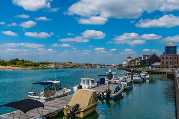 Fototapeta na wymiar A view past boat moorings on the River Arun towards the town of Littlehampton in early summer