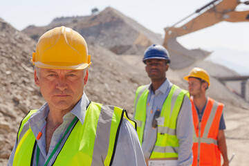 Businessman standing by car in quarry