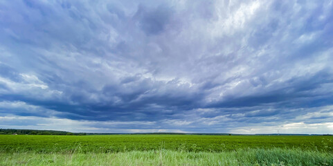 Huge purple storm clouds over a green field. Copy space
