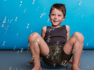 Amazed boy in studio with floating soap bubbles
