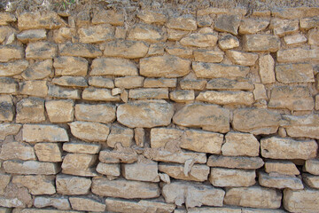 The rough textured surface of the wild stone wall. Background.
