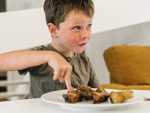 Cheerful boy with plate of food during lunch at home