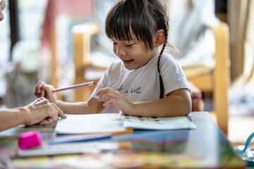 A cute 3-year-old Asian girl is practicing writing and reading. It is an image that focuses on the...